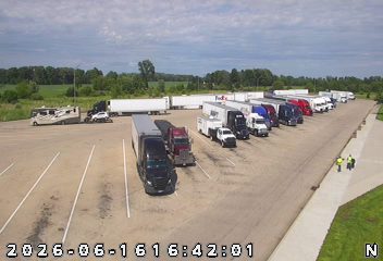 Two individuals in safety vests appear to be responding to something in a parking lot.