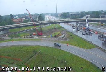 Construction zone with cranes and trucks on a wet highway.