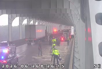 Multiple vehicles and personnel on the roadway under a bridge