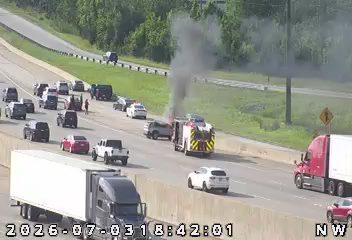 Fire and smoke from a vehicle in the right lane, with a fire truck present