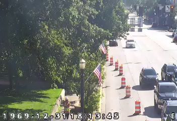 Construction worker with safety vest and cones on the side of the road.