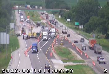 Construction vehicles and cones indicate a possible incident or work zone on the highway.