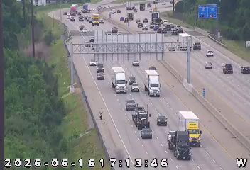Police officer on the shoulder of a busy highway with traffic.