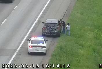 Police car and people on the shoulder near a vehicle with a bike rack.