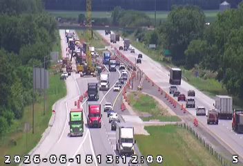 Emergency responders and traffic control are present on the highway, causing a traffic backup.