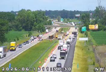 Emergency responders and construction vehicles are present on the highway, causing traffic delays.