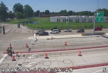 Construction workers and equipment are present on the roadway, indicating ongoing work.