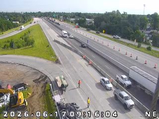 Construction workers and equipment are present on the roadway, indicating ongoing work.