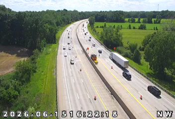 Emergency responders and vehicles on the highway shoulder with traffic cones.