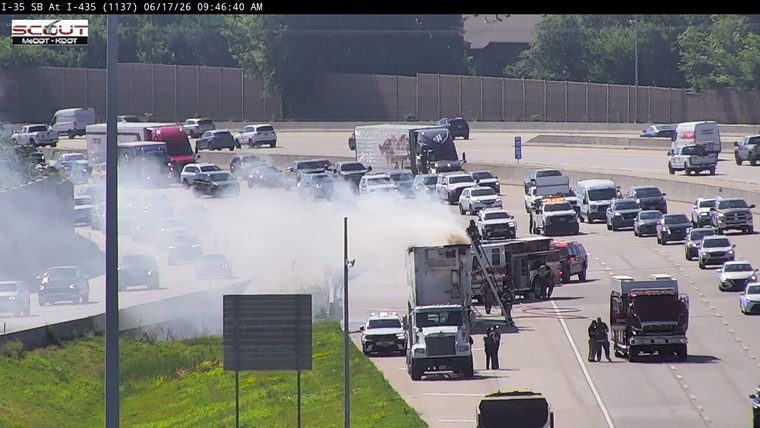 Firefighters are responding to a truck fire on the highway with heavy smoke.