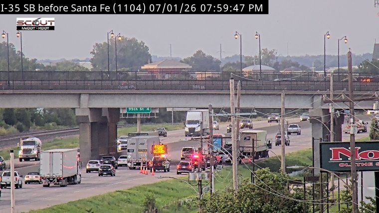 Police car with red and blue lights on the roadway with traffic cones and a 'RIGHT LANE CLOSED' sign