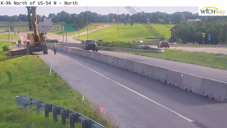 Construction worker and equipment on the side of the road, traffic moving normally.