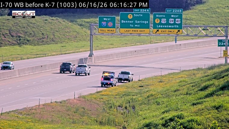 Police vehicle with lights on, stopped on the shoulder with another vehicle.