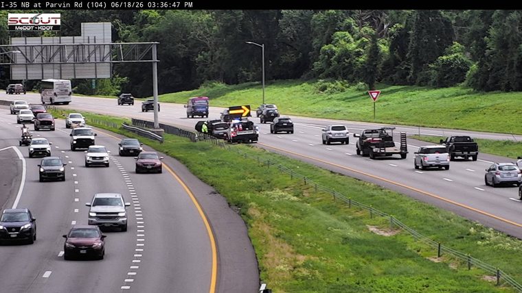 Police car with lights on the shoulder next to a damaged vehicle