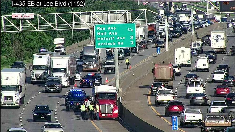 Police cars with lights on and officers attending to a red truck in the right lane
