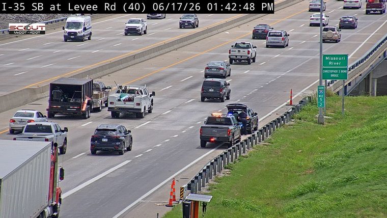 Police car with lights on attending to a stopped vehicle on the shoulder.