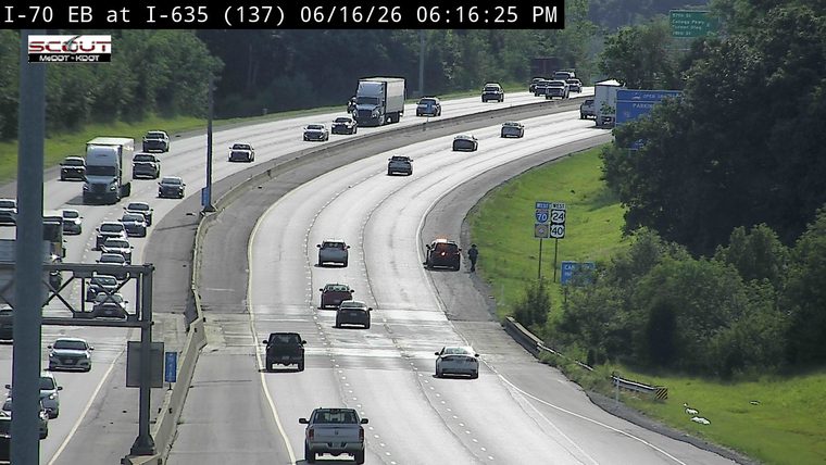 Police car and person on the shoulder of the highway.