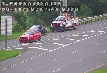 A tow truck and two cars are stopped on the side of the road.