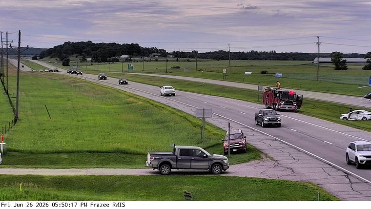 Fire truck with red lights on the right shoulder next to a damaged white car