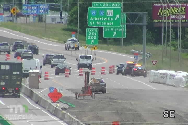 Police cars with lights on at a construction zone with traffic cones.