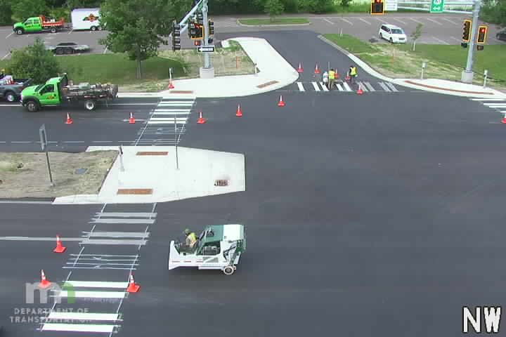 Road crew working on new crosswalk with cones and equipment.