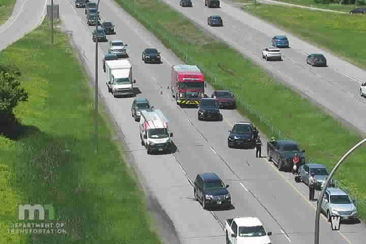 Police officers are attending to a stopped vehicle on the shoulder of the highway.