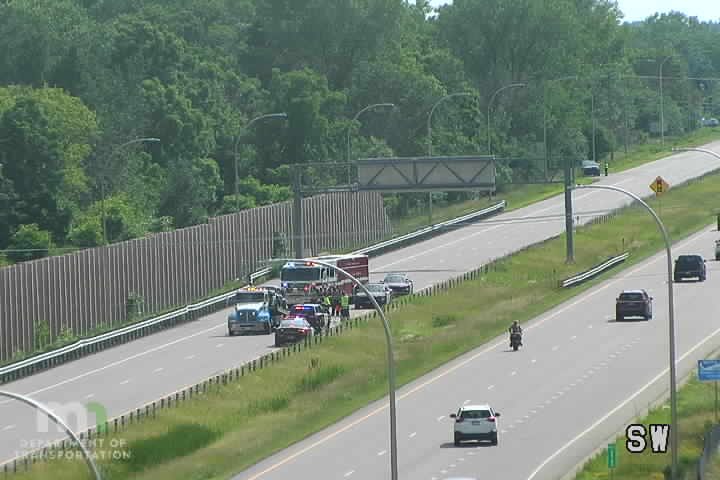 Police car, fire truck, and tow truck on the right shoulder with multiple people visible