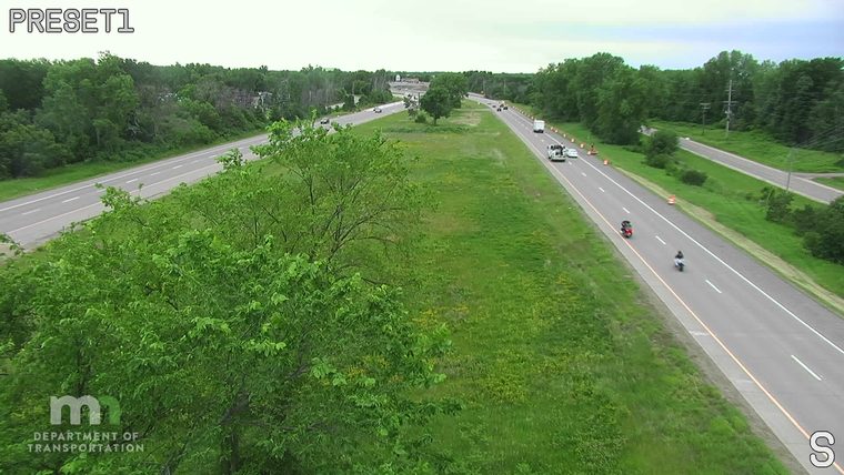 Traffic cones and a white vehicle are on the shoulder of the highway.