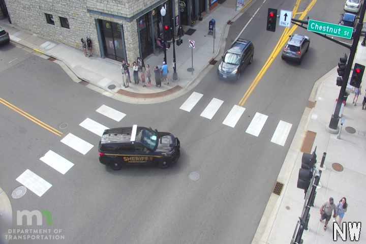 A sheriff's vehicle is present at an intersection with pedestrians nearby.