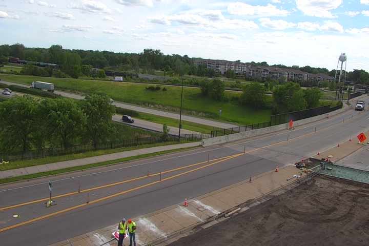 Two construction workers are present on the roadside, indicating ongoing work.