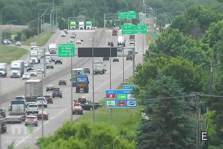 Emergency responders and vehicles are present on the right shoulder of the highway.