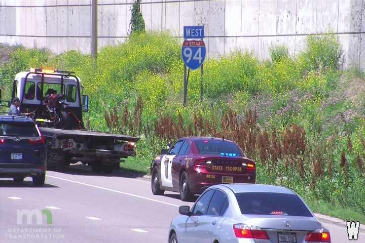 State trooper and tow truck on roadside assisting with a vehicle.