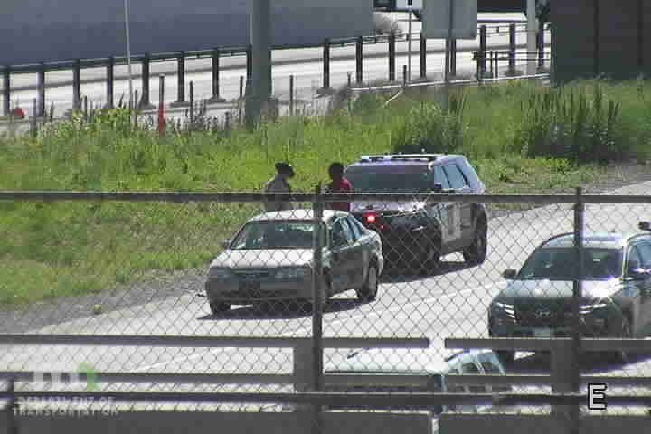 Police car and two individuals on the side of the road.