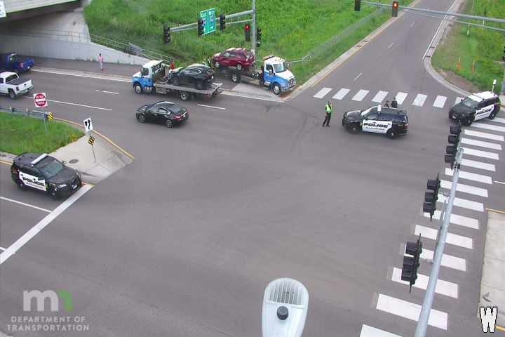 Two police cars and a person in a high-visibility vest at an intersection