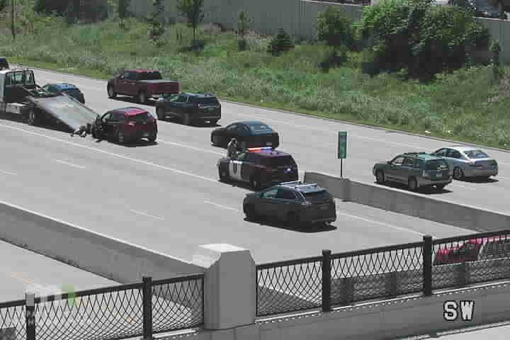 Police car and tow truck at a roadside incident with a damaged car.