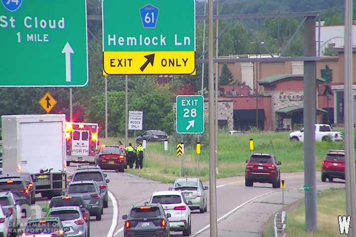 Ambulance and two police cars with officers present on the right shoulder