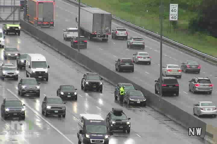 Police car and person in yellow vest on the highway shoulder.