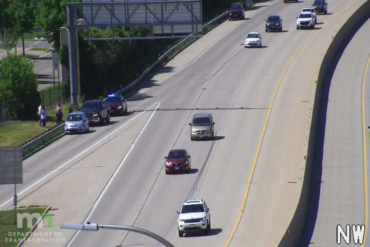 Police and other vehicles stopped on the shoulder with people present.