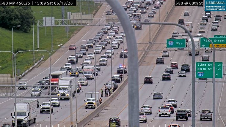 Police and other personnel are on the shoulder of the highway with vehicles.