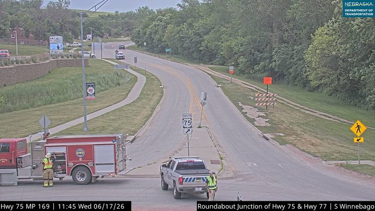 Fire truck and police vehicle with personnel on scene at highway junction.