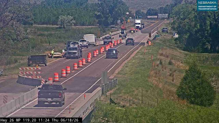 Construction zone with workers and traffic cones, traffic is moving.