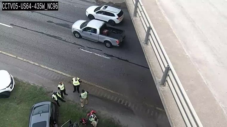 Police officers and a civilian near a car off the roadway