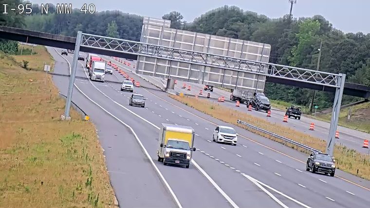 Debris on roadway, traffic cones, and a damaged vehicle blocking lanes.
