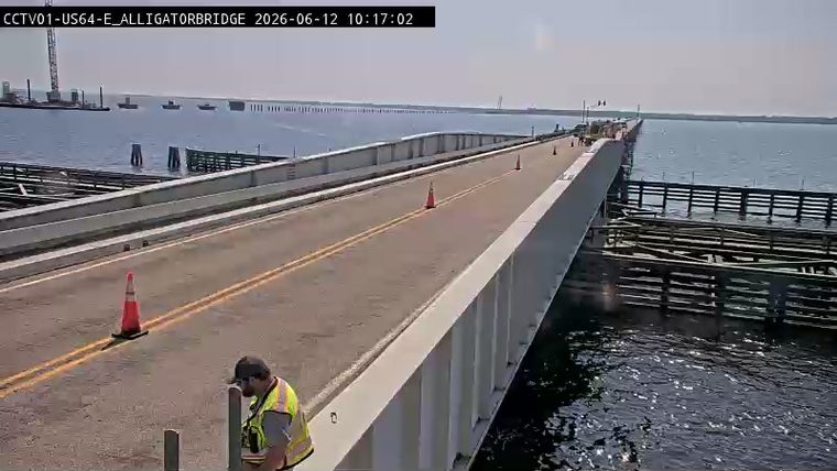 Worker in safety vest on bridge, cones present, indicating possible work or incident.