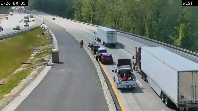 Police and tow truck responding to a vehicle on the shoulder.