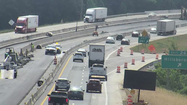 Road work with personnel and equipment on the shoulder and in travel lanes.