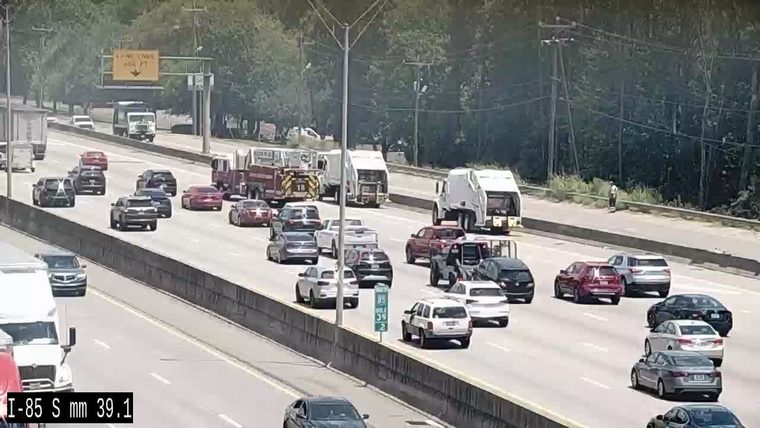 Fire truck and other vehicles on the side of the highway with a person present.