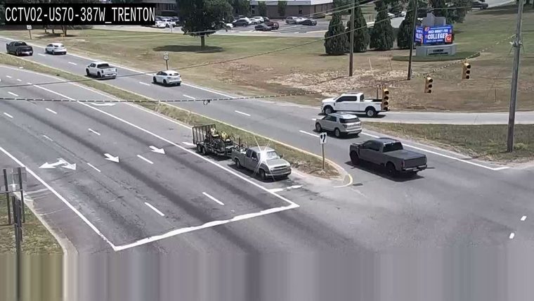 Two people in a truck with a trailer appear to be working on the roadside.
