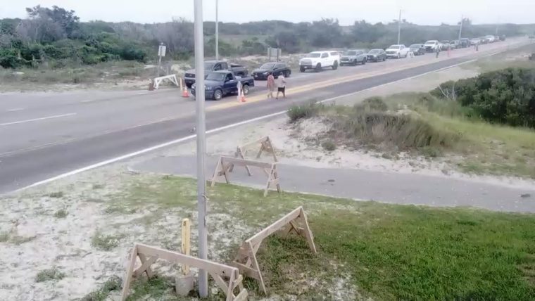 Traffic stopped due to cones and barriers, people directing traffic.