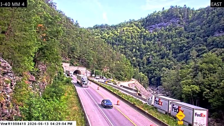 Emergency responders and vehicles are present near a tunnel entrance.